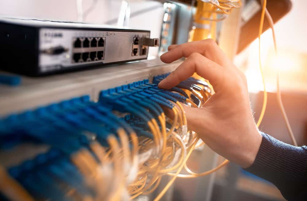 An engineer installs fiber optic patch cables at a customer site that’s part of an ISP network architecture.